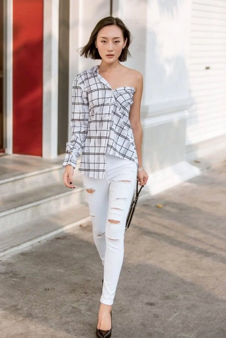 Biến áo sơ mi đứng đắn quen thuộc thành áo trễ vai sexy. Chị em chỉ cần mặc chiếc áo sơ mi để mở 2 cúc áo đầu tiên rồi kéo cổ áo trễ về phía sau nhằm để lộ ra phần vai thon thả.