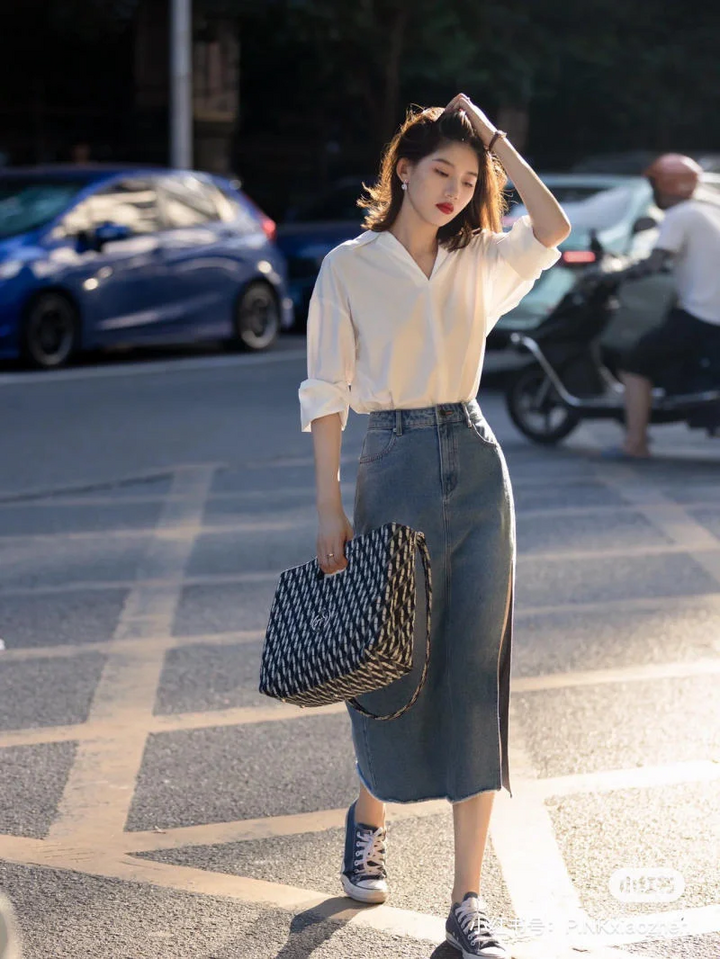 Sự kết hợp giữa chân váy jeans xẻ tà dáng dài và áo sơ mi trắng cổ đức hoặc cổ V mang đến một vẻ ngoài thanh lịch và trẻ trung. Đây là một set đồ phù hợp với nhiều hoàn cảnh khác nhau, từ đi làm đến đi chơi.